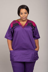 Woman wearing a purple African print scrub with colorful accents on a plain background