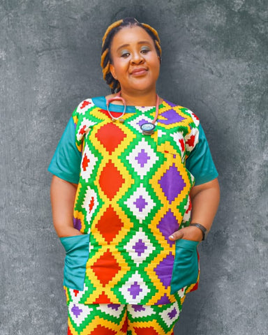 Person wearing a colorful diamond patterned outfit against a gray background