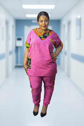 A woman standing against a gray background, wearing a pink, floral trimmed track scrub .