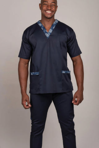 Man wearing a navy blue scrub set with decorative elements on a plain background